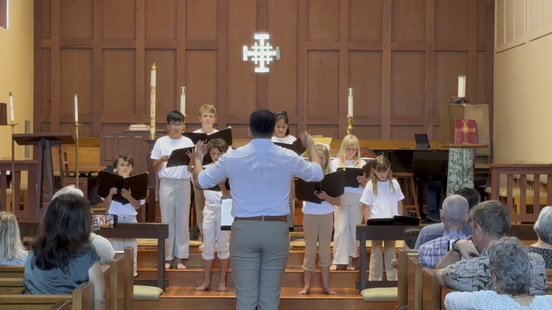 Director conducting the children’s chorus during a performance for the congregation