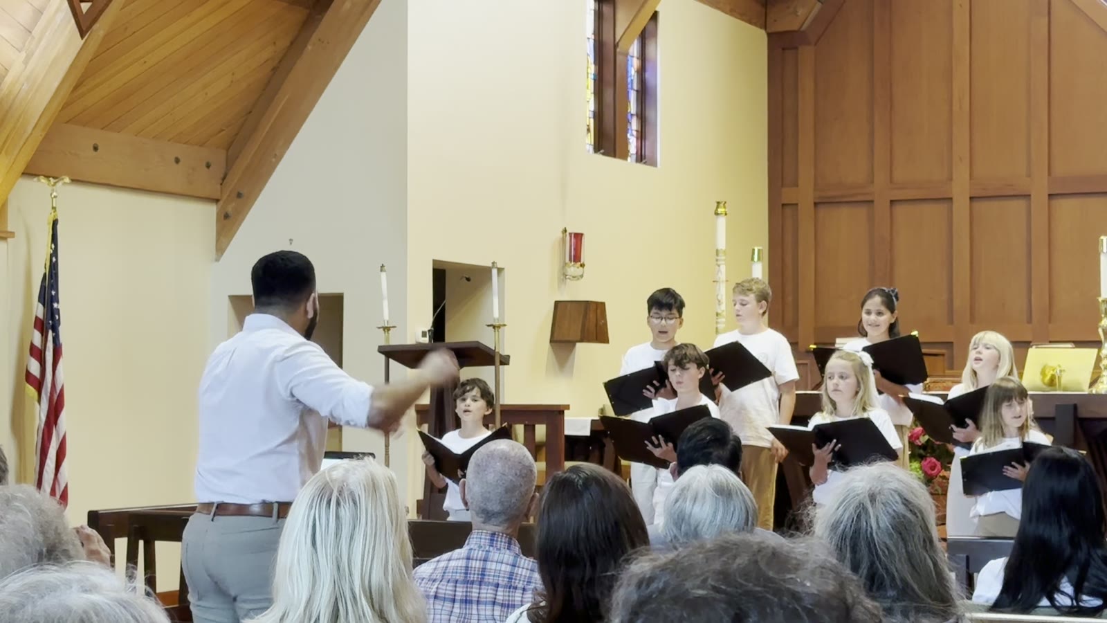 Singers holding black folders, watching the director closely